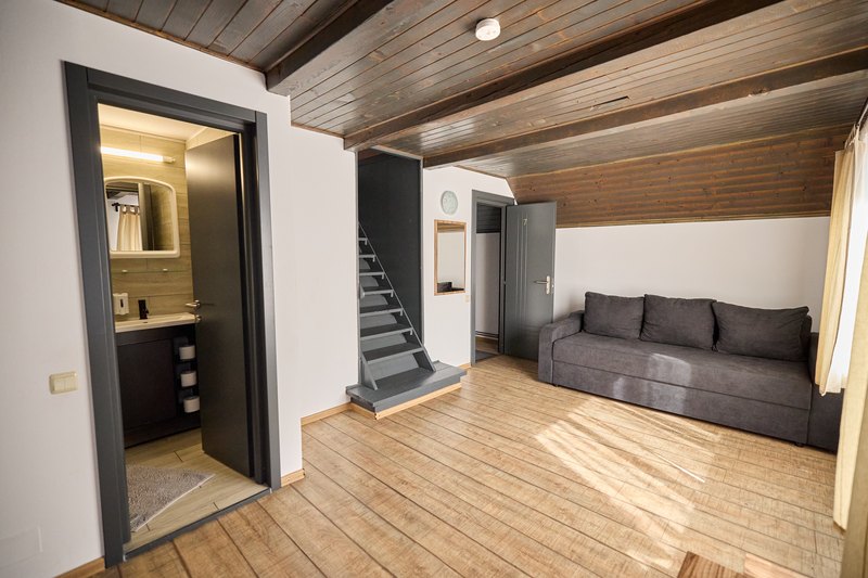 Apartament cu 3 dormitoare — canapea și scară spre mansardă